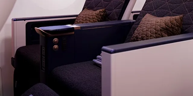 Kursi Premium Economy Riyadh Air dengan bantal dan panel kontrol di sandaran tangan